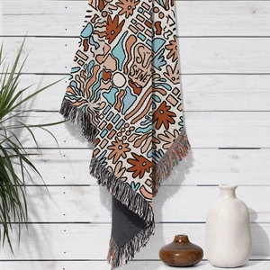 Detail showing the woven sunshine pattern and colorful tassel edges of a bohemian picnic blanket