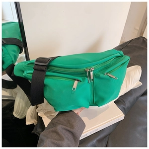 Detail of green nylon crossbody bag with multiple zippers and wide adjustable canvas strap