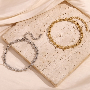 Detailed close-up of U-link chain bracelets in 14K gold and silver plating on stone surface