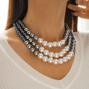 Detail of three-layer gradient pearl necklace with white, grey, and black beads on model