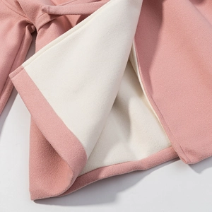 Dettaglio del cappotto di lana rosa che mostra la fodera in pile bianco e il tessuto