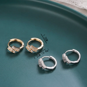 Detail shot of 1.2cm gold and silver hoop earrings with zircon insets on a green plate
