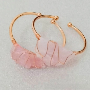 Detail of rose gold wire-wrapped open cuff bracelet with irregular natural rose quartz stone