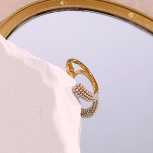 Detail of gold open ring with micro-pave white beads on white rock and mirror