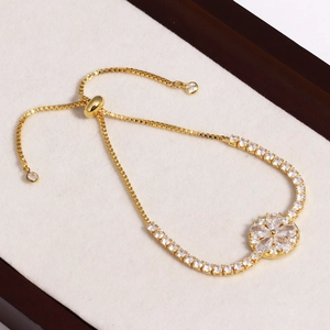 Détail d'un bracelet bolo réglable en or avec fleur en zircon et boucle coulissante brillante