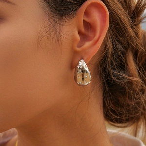 Close-up of teardrop earrings in silver finish with pavé set zircon stones on model
