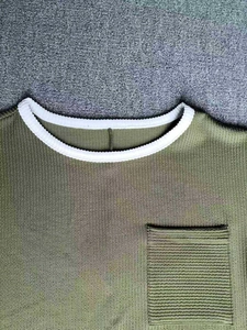 Gros plan du t-shirt vert olive en tricot côtelé avec col rond blanc contrasté et poche