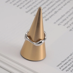 Close-up of S925 sterling silver wavy ring on a gold stand over an open book