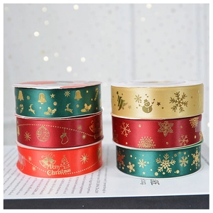 Close-up of 2.5cm satin ribbons with gold snowflake and reindeer festive patterns