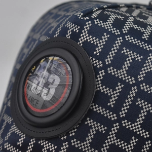 Macro shot of navy blue fabric with white H jacquard pattern and leather badge detail