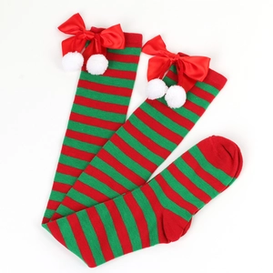 Detail of over-knee Christmas socks with red-green stripes, bows and white fuzzy balls