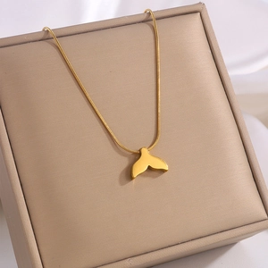 Detail of a golden fish tail pendant on a thin chain over an elegant jewelry box