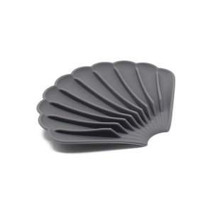 Detail of grey shell-shaped silicone soap dish with drainage slots on white background