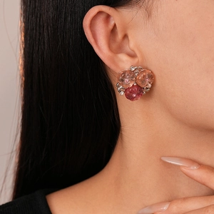 Detailed close-up of pink resin flower stud earrings with rhinestones on a female model
