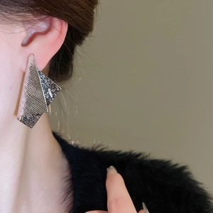 Detail shot of silver irregular geometric metal earrings with textured finish on model