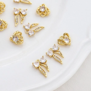 Macro view of 14k gold plated heart and bow pendants with micro-set zircon stones