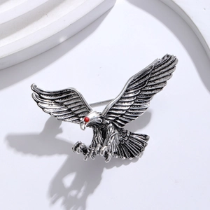 Detail of vintage eagle brooch with silver metal texture and red rhinestone eye
