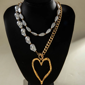 Detailed macro view of baroque pearl stitching and golden heart pendant on layered necklace