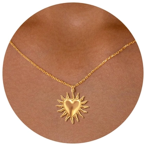 Detail of a golden heart sunburst pendant necklace with radiant rays worn on the neck