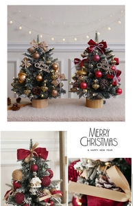Close-up of mini Christmas tree with warm lights, pine cones, and festive ornaments