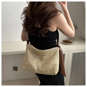Detail showing handwoven straw tote with brown leather knot and silver chain strap