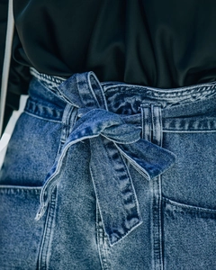 Dettaglio dei pantaloncini di jeans blu con cintura in vita e trama del tessuto denim