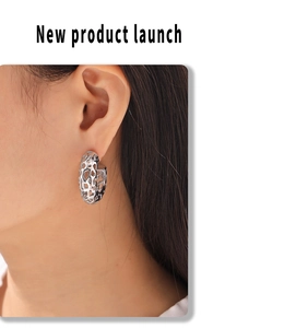 Detail view of irregular hollow C-shaped hoop earrings with grid texture on ear