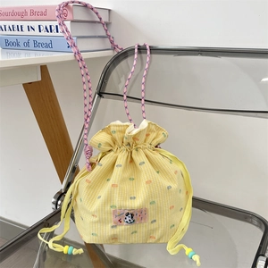 Detail of yellow checkered drawstring bag with colorful embroidery and cow patch