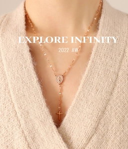 Rose gold Y-shaped necklace with embossed religious coin and cross pendant on a model