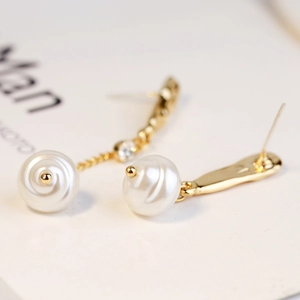Detail of baroque pearl drop earring with gold twist texture and sparkling zircon stone