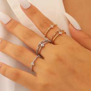Detail of layered gold and silver rings with small zircons on a hand with white nails