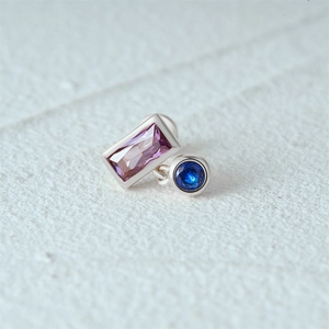Close-up of S925 silver ear stud with rectangular purple and round blue opal gemstones