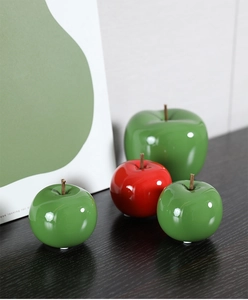 Pommes en céramique rouge et verte brillantes avec tiges sur une surface en bois
