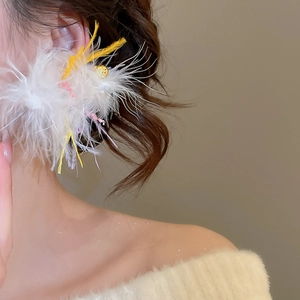 Close-up of elegant white feather earrings with gold bead detail on a model