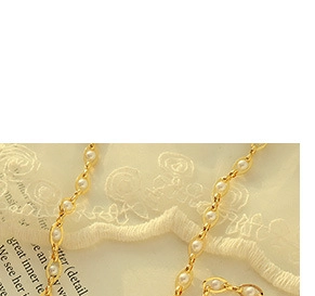 Close-up of vintage French style gold-plated necklace with oval metal and white pearls