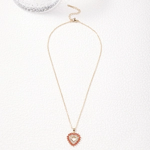 Golden heart pendant necklace featuring red and white cubic zirconia on a white surface