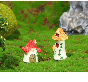 Miniature resin fairy garden houses with red and orange roofs on green moss detail