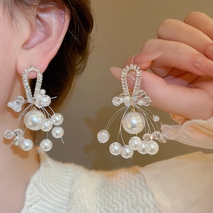 Detailed close-up of luxurious pearl and crystal drop earrings with gold-tone base