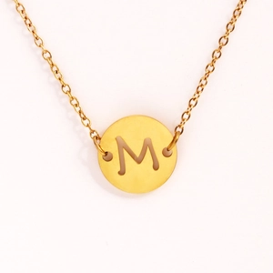 Vue détaillée d'un collier doré en acier inoxydable avec pendentif rond lettre M ajourée