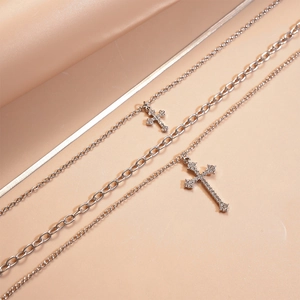 Detail of layered silver necklaces with rhinestone cross pendants and snake chain
