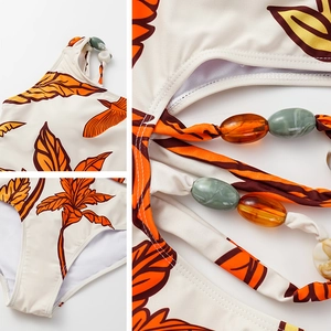 Detail of beaded leaf print swimsuit featuring tropical patterns and resin bead decor