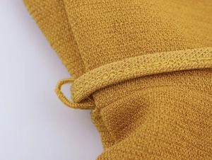Vista macro della trama in maglia giallo zenzero e dettagli dell'asola del collo