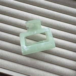 Detail view of light green marble rectangle hair claw clip on jewelry display tray