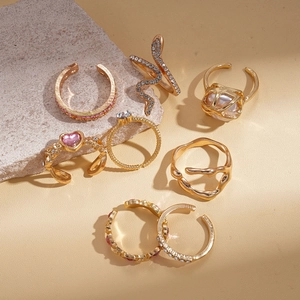Detail of 7-piece bohemian gold ring set with rhinestones and pearls on natural rock