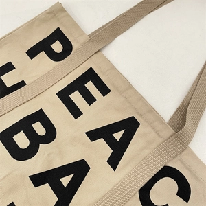 Close-up of the black PEACE letter printing and texture on a khaki canvas tote bag
