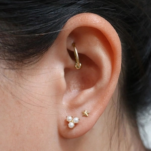 Detail of s925 silver pearl stud and gold star earring set on earlobe model