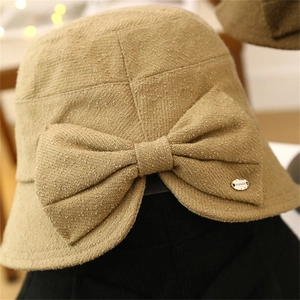 Close-up of oatmeal textured bucket hat with a large bow and metallic logo detail
