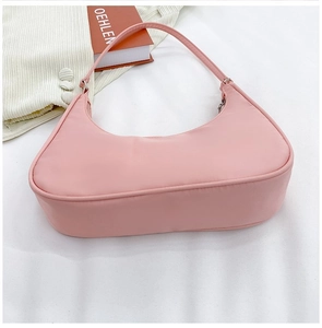 Detailed top view of pink nylon hobo bag on white fabric with casual lifestyle props