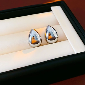 Primo piano di orecchini a goccia in argento lucido in una scatola regalo di lusso