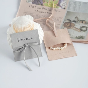 Gray and pink microfiber jewelry pouches with pearls on vintage newspaper background